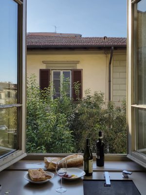 Focaccia bread and wine facing a big wide open window plants and a house in Italy