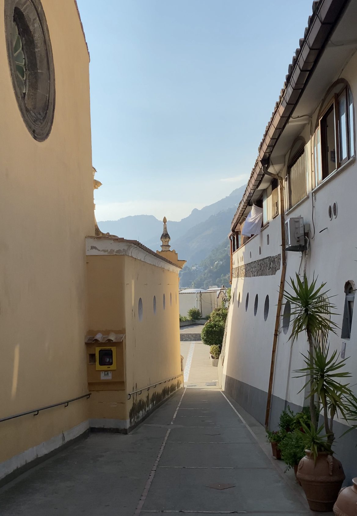 Narrow street between two typical buildings with mountains and blu sky background at Praiano in Campania, Italy