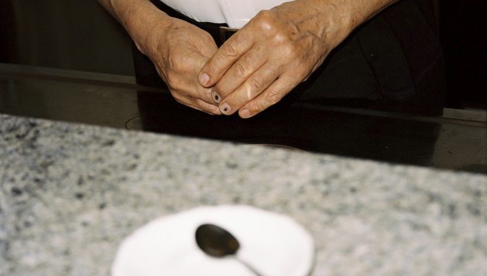 Franco Vitto formal dressed in behind a bar's counter with a little plate and spoon at Caffè dell'Incontro in Conversano Puglia in italy