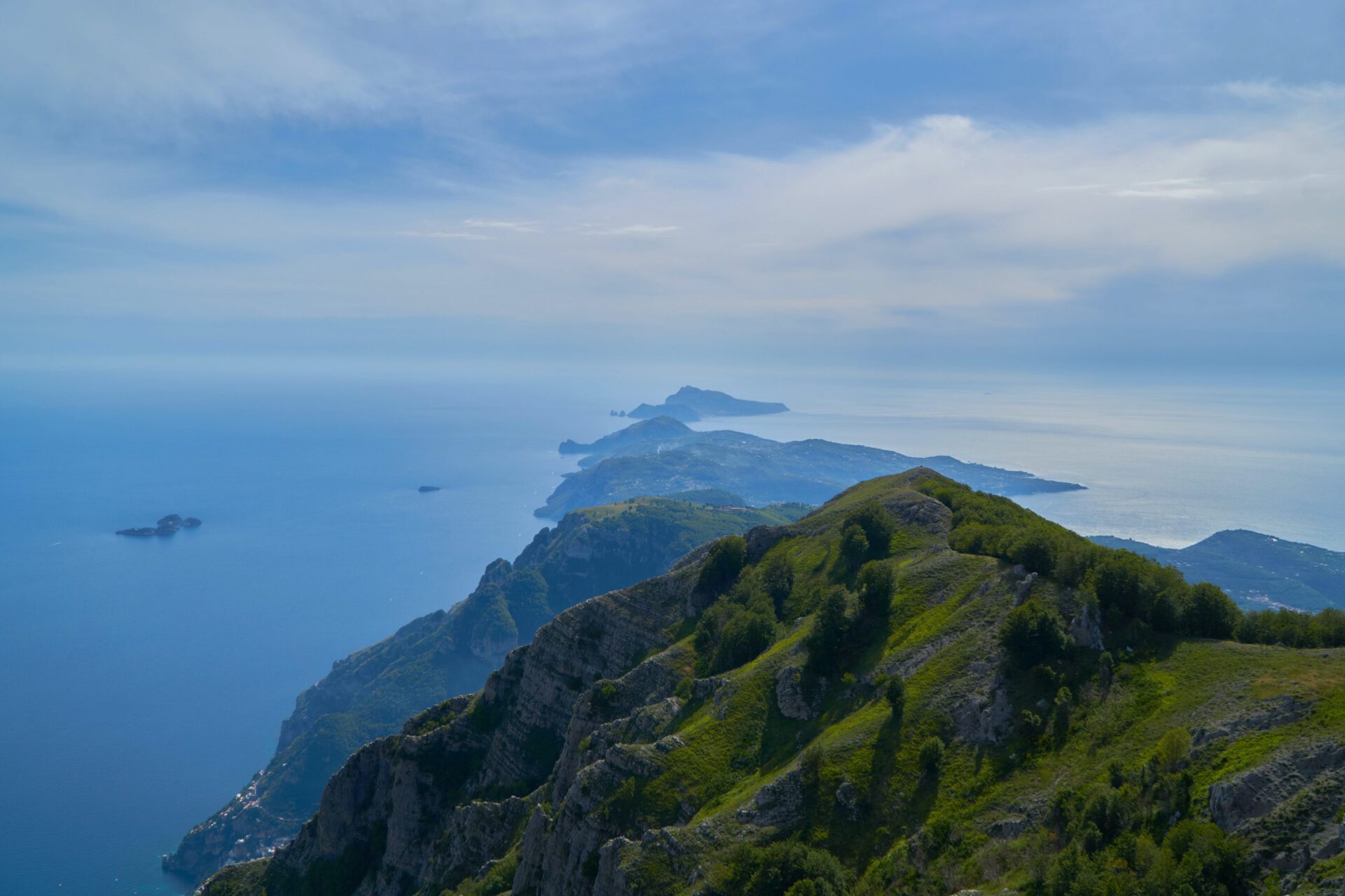 Chain of green and dark mountains with rocks crossing by the ocean with blue bright water Vico Equense in Campania, Italy