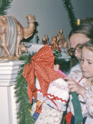 Old picture of a mom and daughter in pijama searching into a sock for presents Epiphany Celebrations