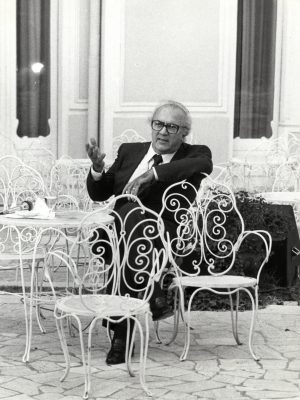 Federico Felini formal dressed with glasses on metallic chairs resting at the Grand Hotel in Rimini Emilia Romagna in black and white in Italy