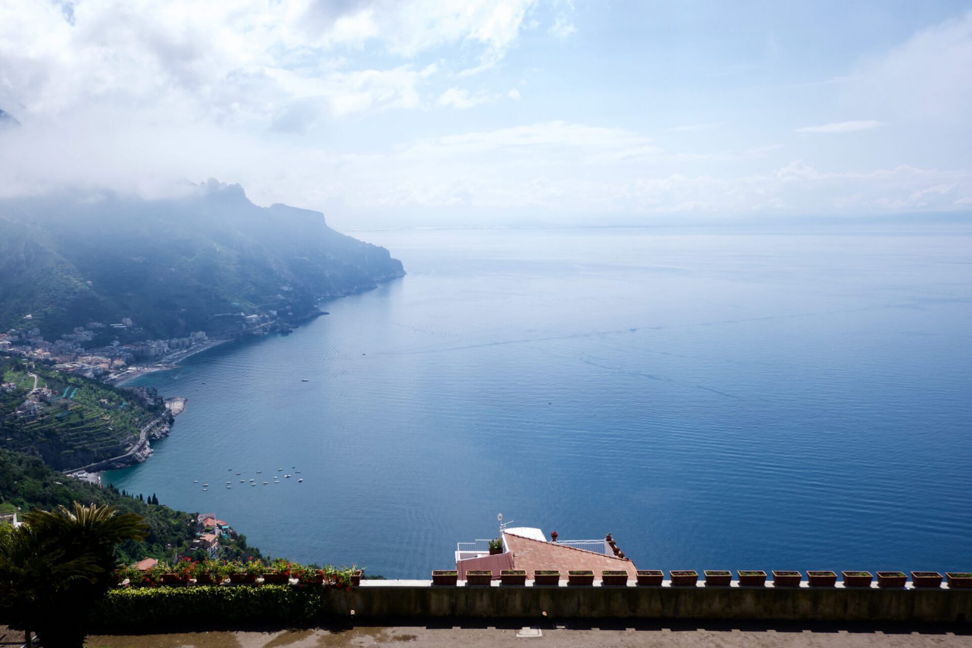 Houses over a green hill surrounded by plants and trees facing the ocean with steps levels on the mountains at Ravello Campania in Italy