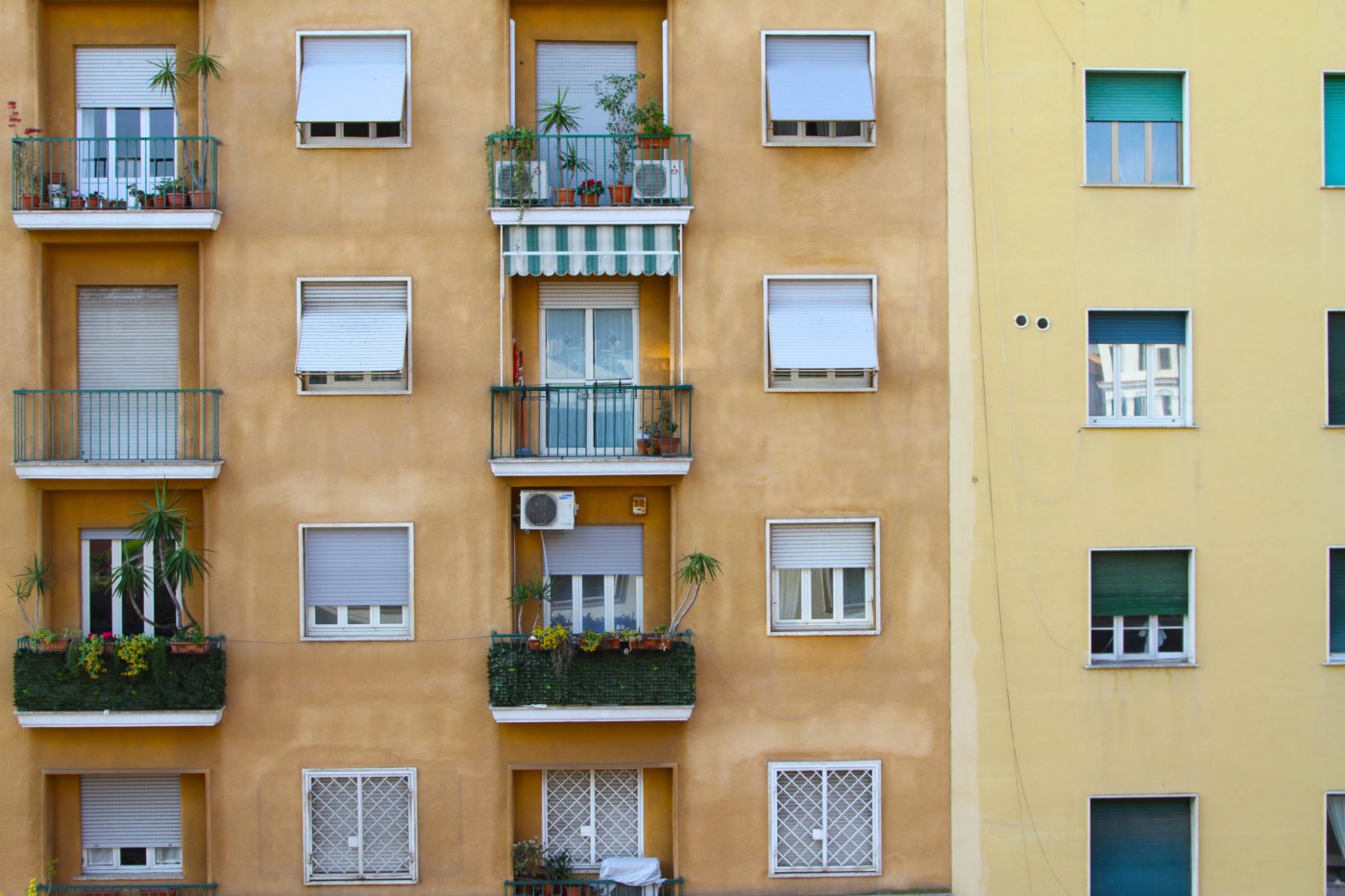 Front view of a typical roman building with closed windows and small terraces filled up with plants and greens in Rome Lazio in Italy