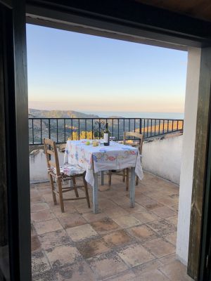 Wooden table with tablecloth wine and glasses over terrace with mountains and sea background in Pietrapaola Calabria in Italy