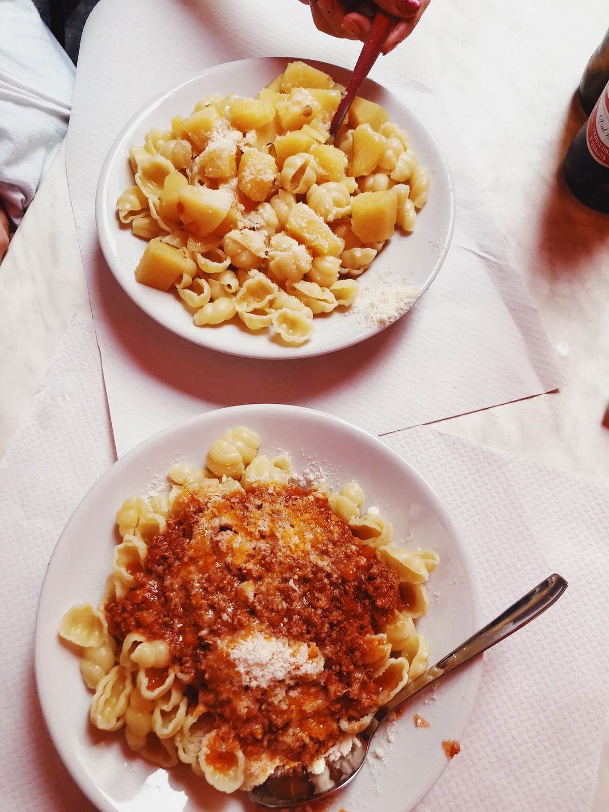 two dishes of rustic homemade pasta, one al ragù and one with butter and potatoes