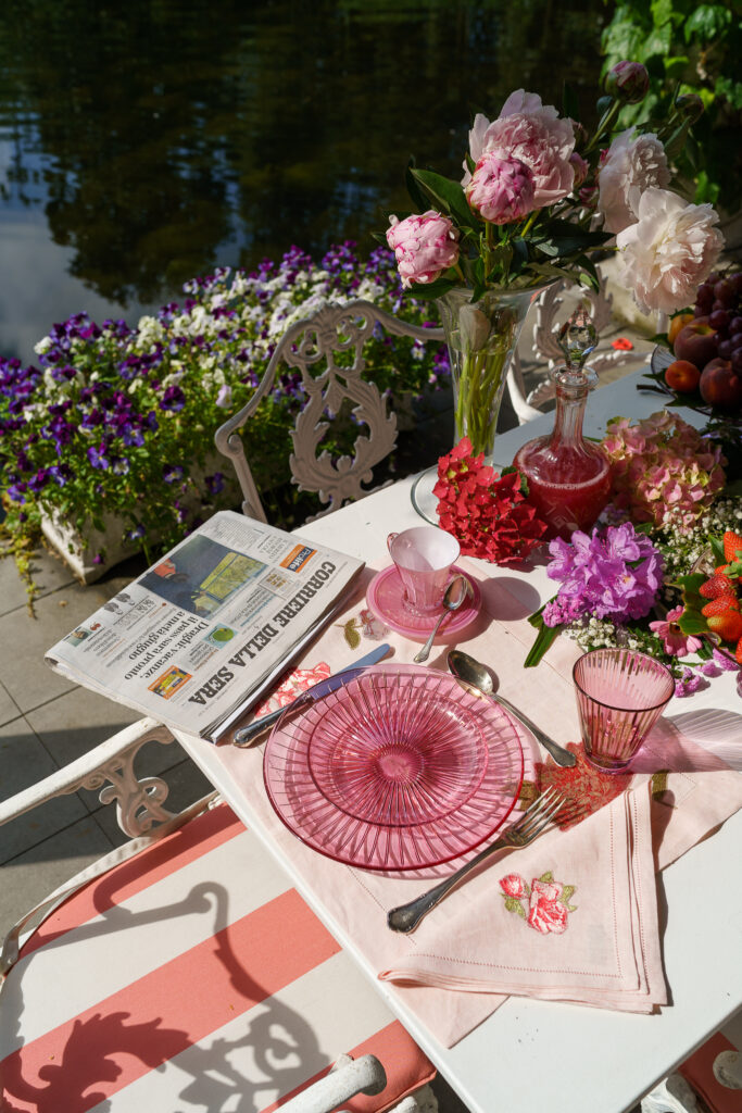 z photo of a table at La Foleia with many flowers and pink plates next to the lake