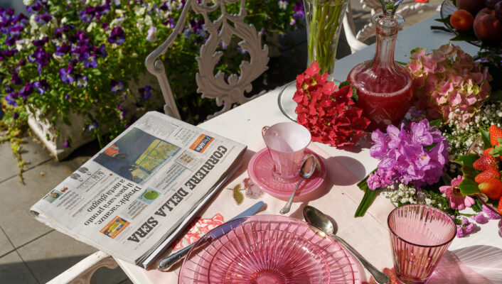 z photo of a table at La Foleia with many flowers and pink plates next to the lake