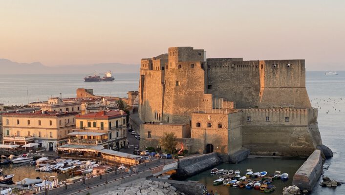 Castel Nuovo in Naples with the sun setting in the background
