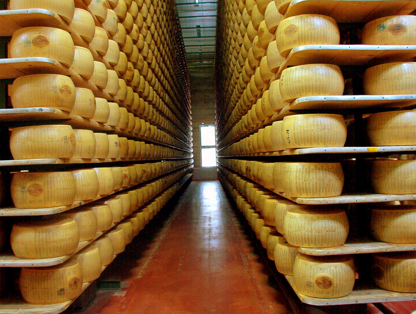 two rows of many shelves of Parmigiano Reggiano