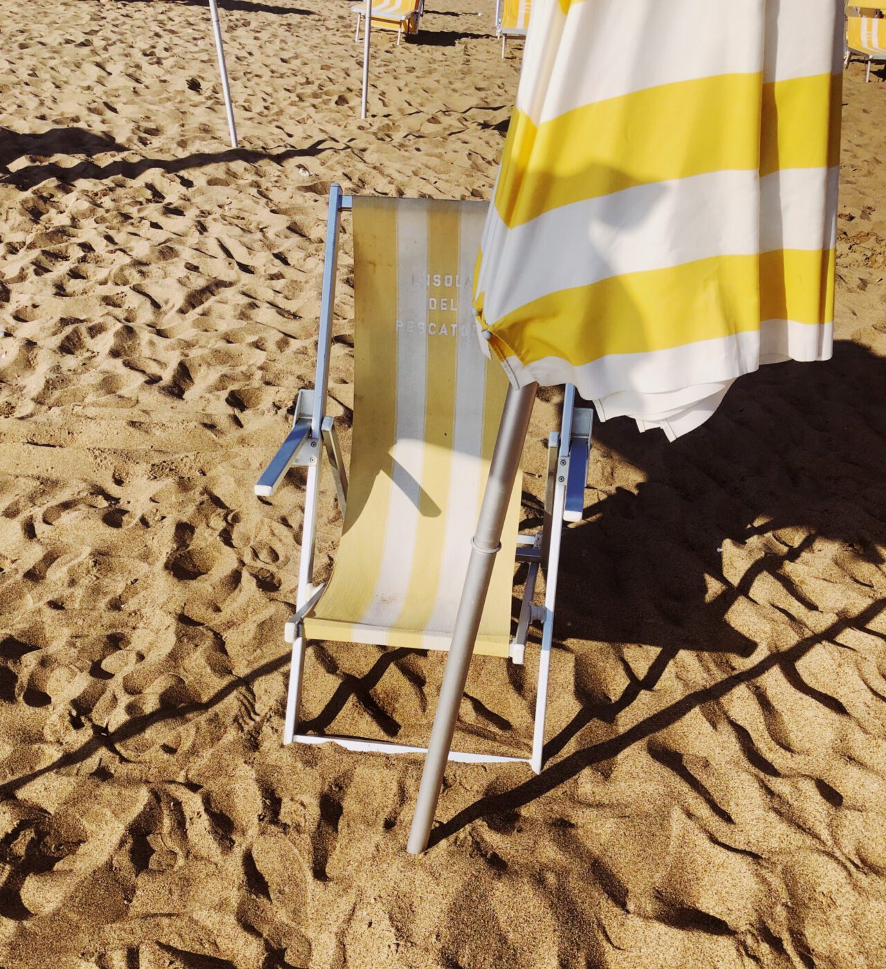 yellow and white striped umbrellas on a sandy beach in Lazio