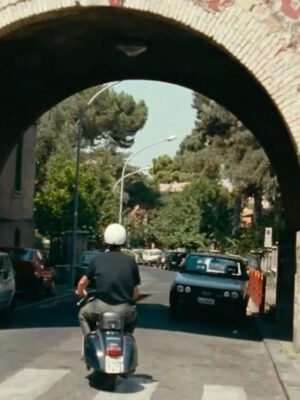 screenshot from Caro Diario of the back of Nanni Moretti riding a vespa under an arch