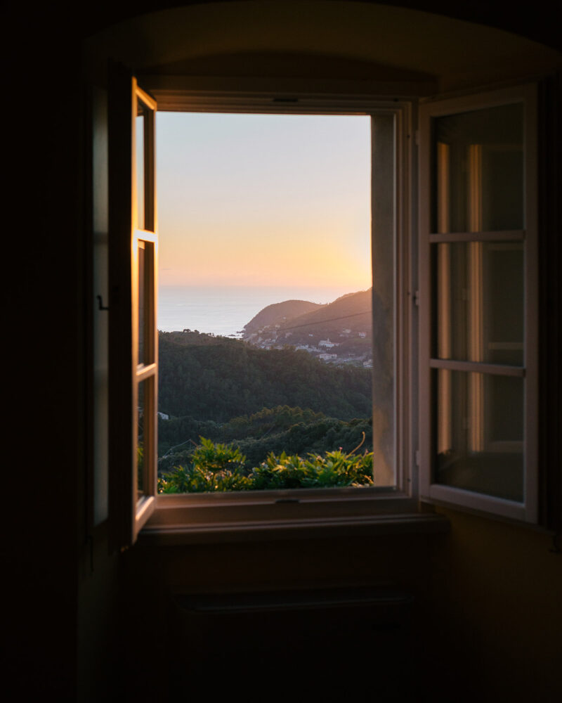 a view of a sunset over the sea out the window of La Sosta di Ottone III