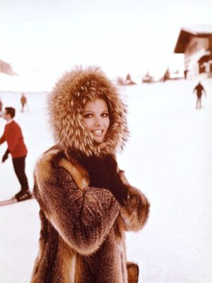 claudia cardinale wearing a thick brown mink coat on a ski slope with the fuzzy hood up around her face