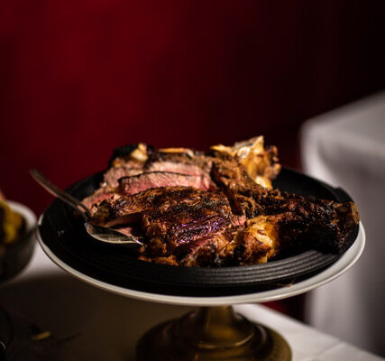 Bistecca alla fiorentina sliced and arranged on an elevated plate in a Tuscan restaurant