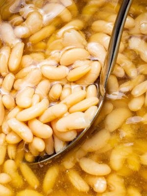 a close up of a bowl filled with white beans in oil