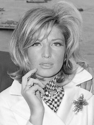 A black and white image of Monica Vitti in the movie Terence Stamp (1965) wearing a white blazer and holding her hand up towards her face