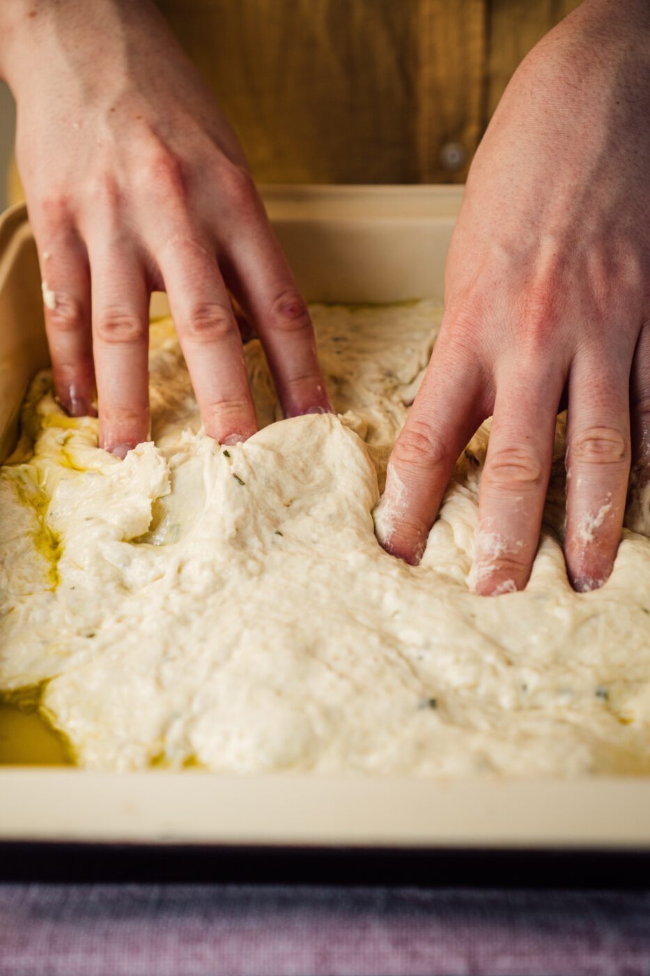 someone poking holes in focaccia dough