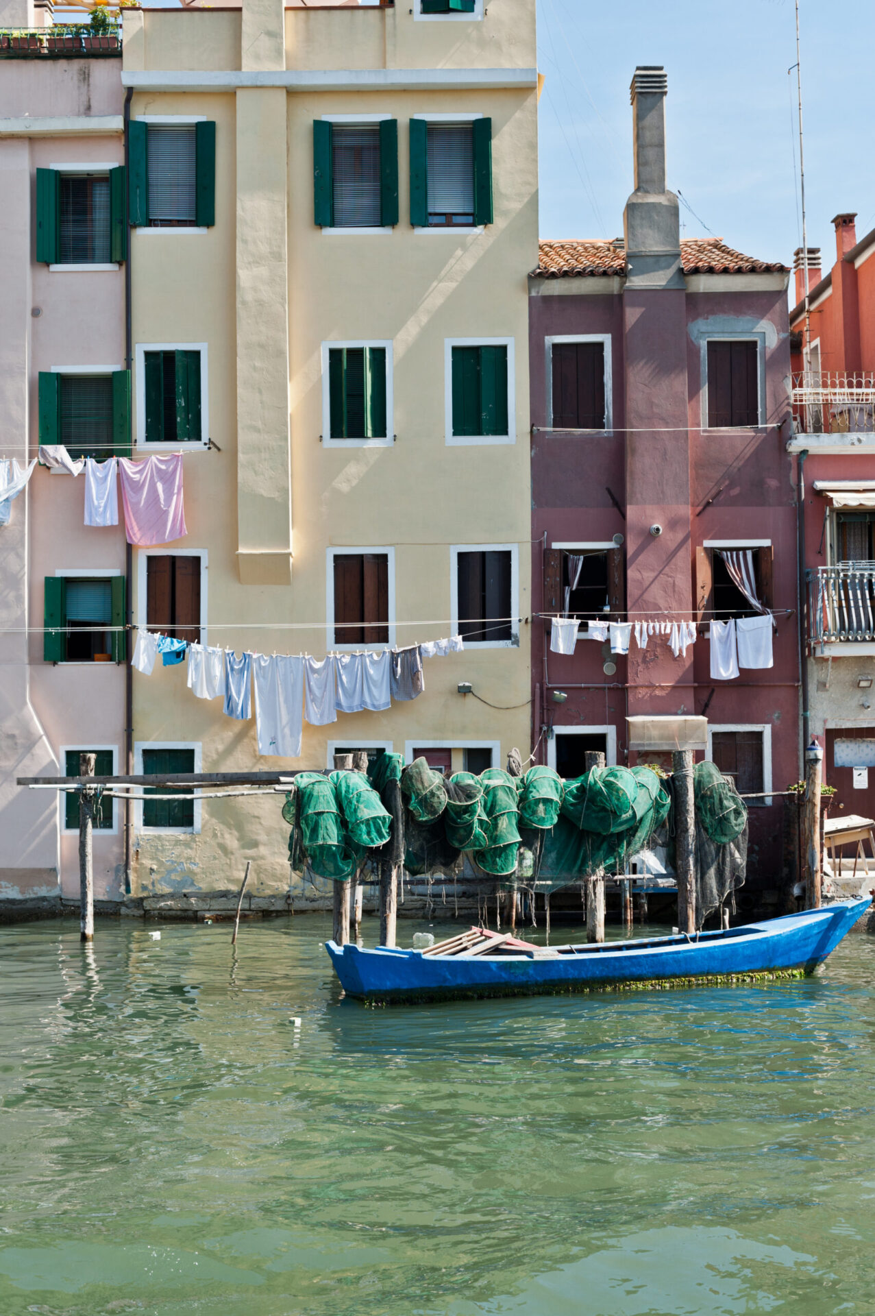 an image of a boat in the canal of Chioggia underneath handing laundry out of the red and yellow apartments