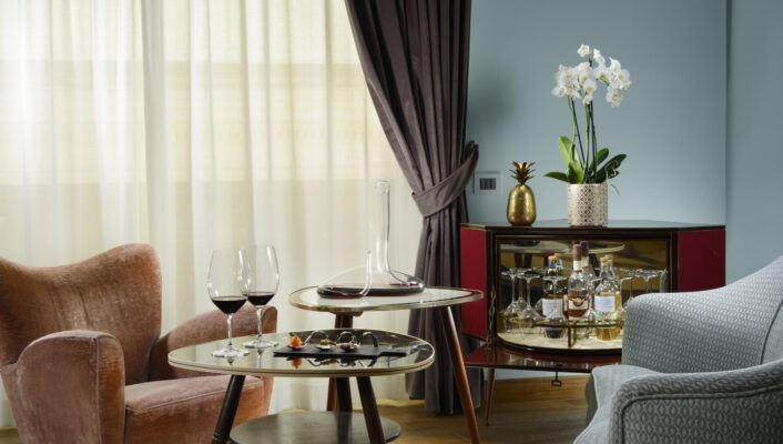 a room at Hotel Dè Ricci with two chairs and a table with wine and snacks