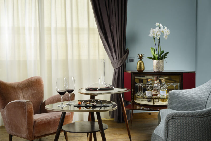 a room at Hotel Dè Ricci with two chairs and a table with wine and snacks