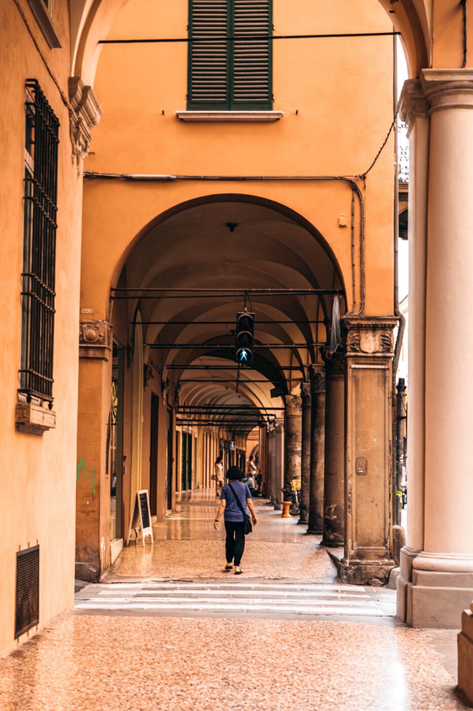 a woman walking alone through Bologna's portici / arcades