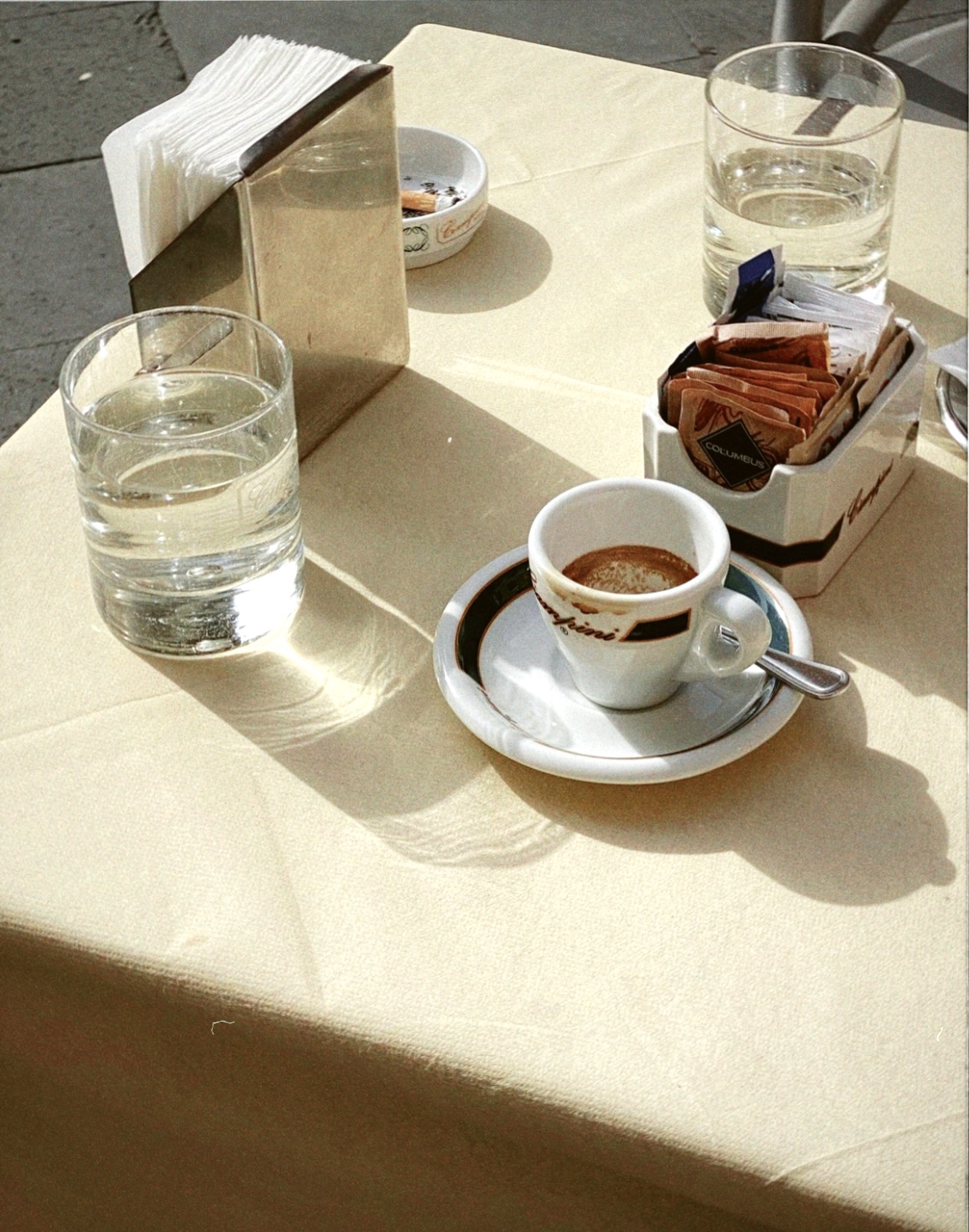 Outdoors Italian bar table filled up with glass cups, espresso coffee cups sugar bags and ashtrays
