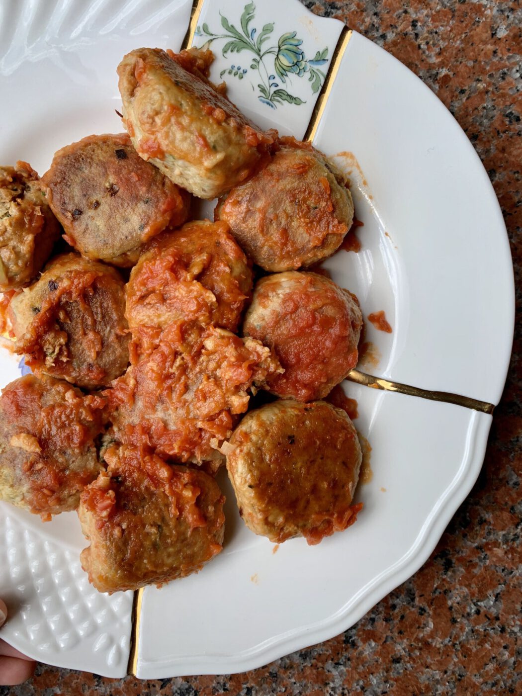 Italian homemade polpette meatballs over bright red tomato sauce and ceramic plate in Italy