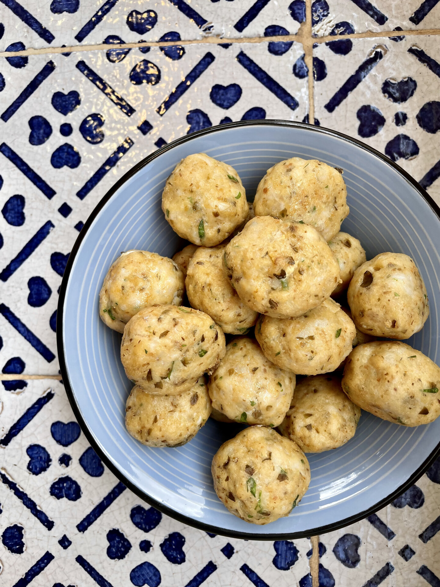 Italian homemade Pallotte Cace e Ova meatballs over blue ceramic plate and patterned floor in Italy
