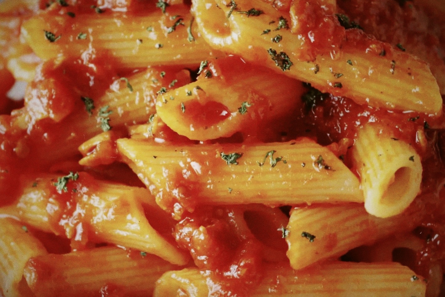 Close up of italian penne all'arrabbiata pasta with tomato sauce and parsley