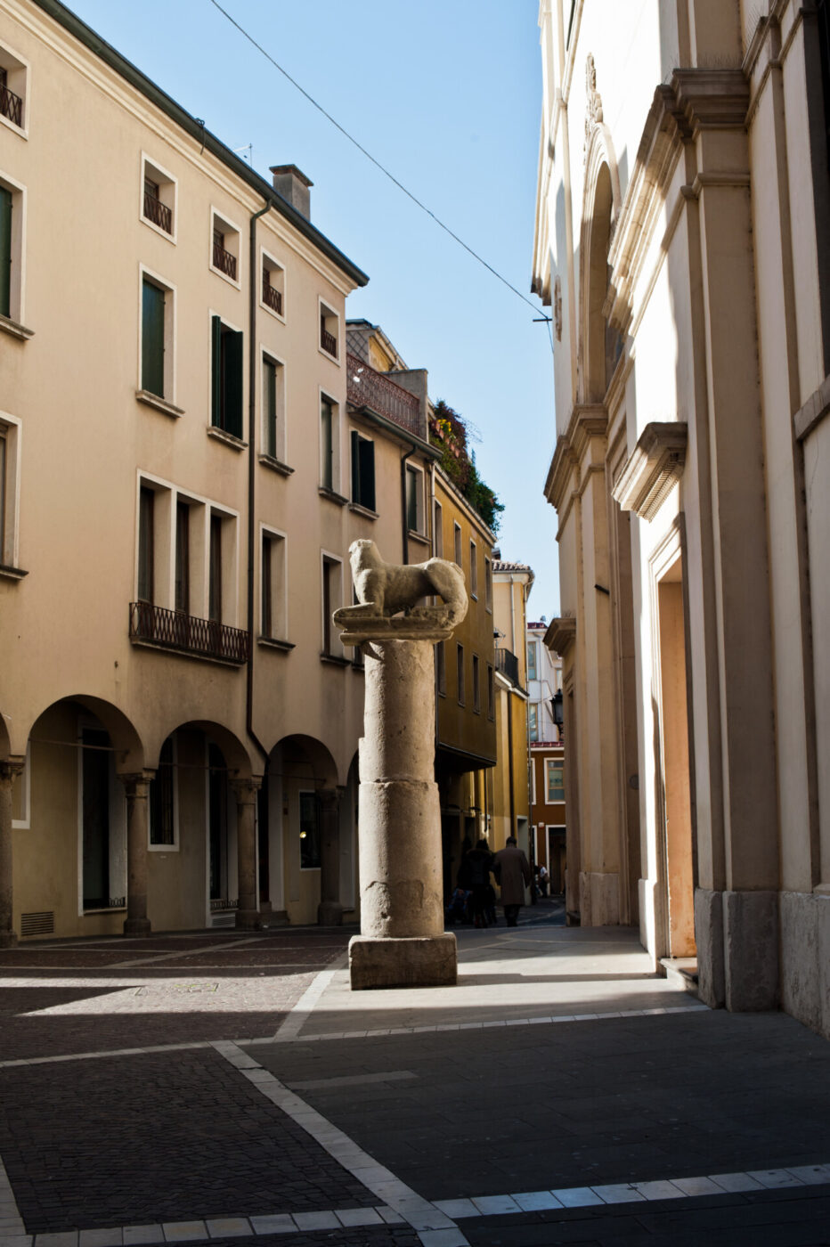 Square with a central sculpture surrounded by typical venetian architecture pink buildings with arches and columns in Padua Veneto in Italy