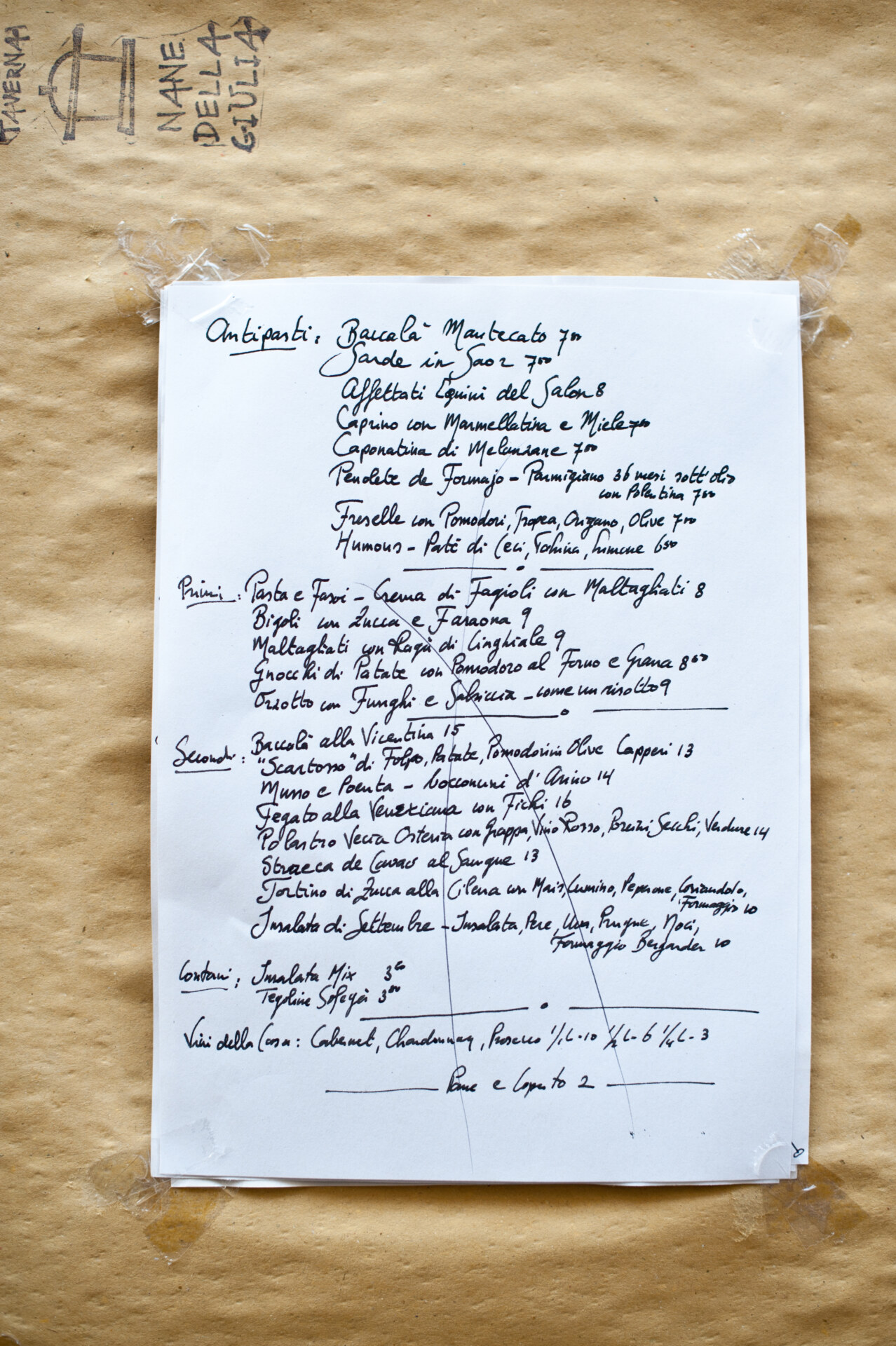 Handwritten white menu of the restaurant taverna nane della giulia over a brown paper sheet in Padua Veneto in Italy