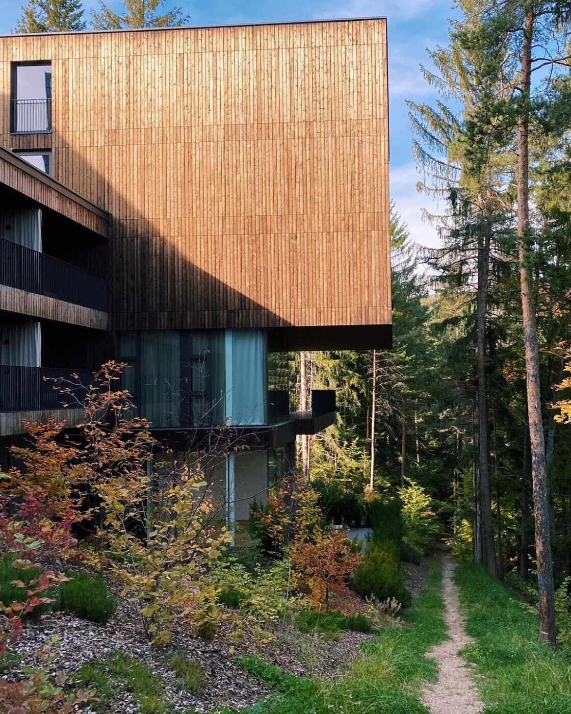 Wooden and crystal structure hotel saltus in the middle of a forest surrounded by trees and plants in Alto Adige in Italy