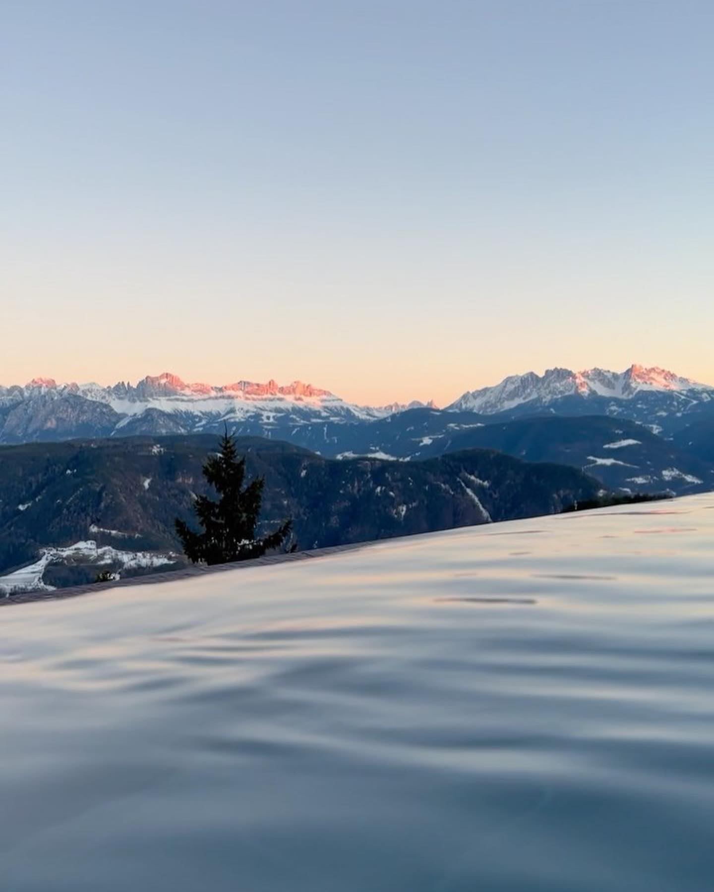 Hotel saltus' swimming pool viewing mountains with plants, trees and covered in snow in Alto Adige in Italy