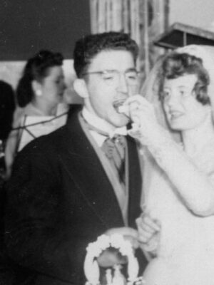 Carmen and Barbara on their wedding day feeding cake to groom