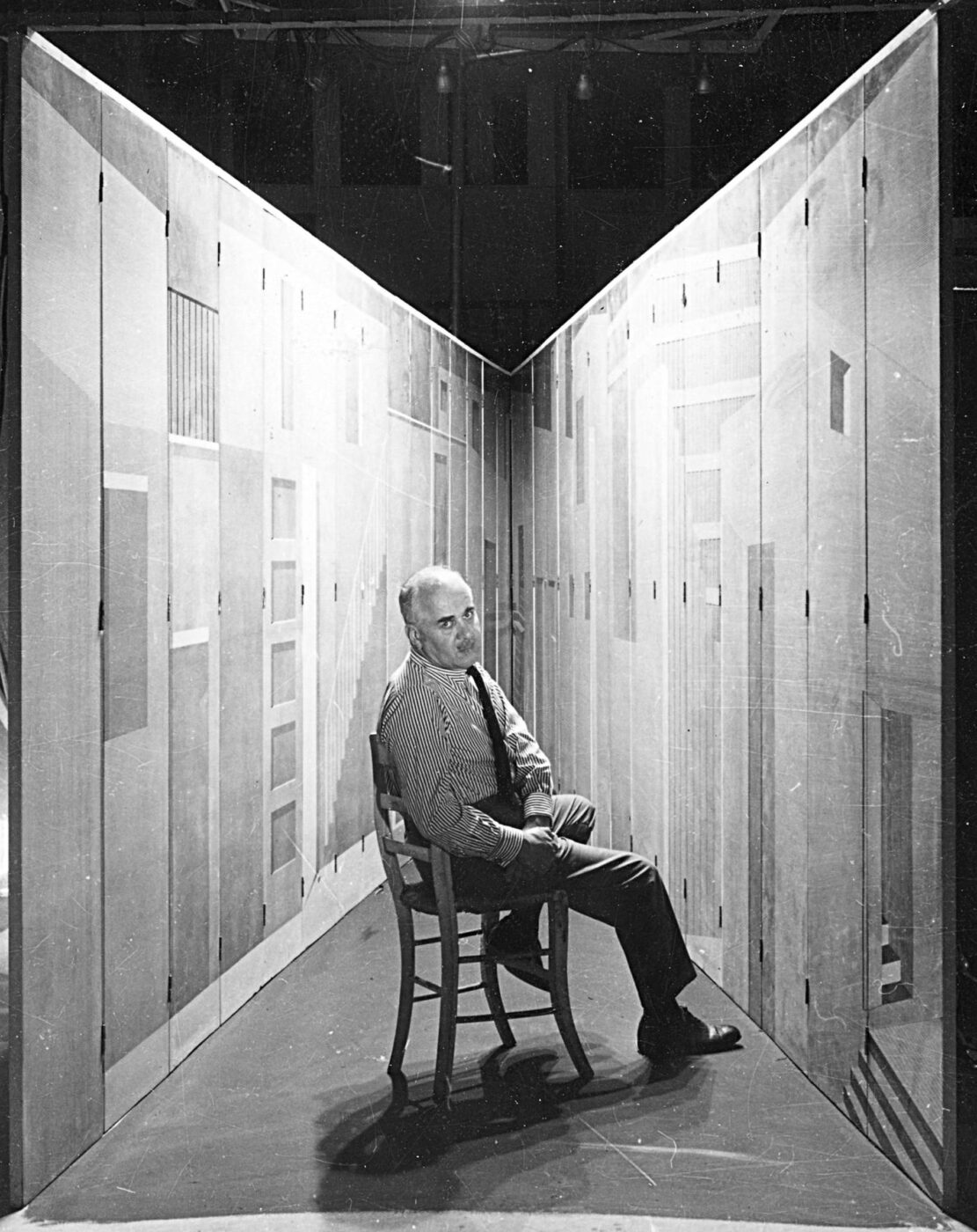 Photograph of the Italian artist Piero Fornasetti sitting in his La Stanza Metafisica
