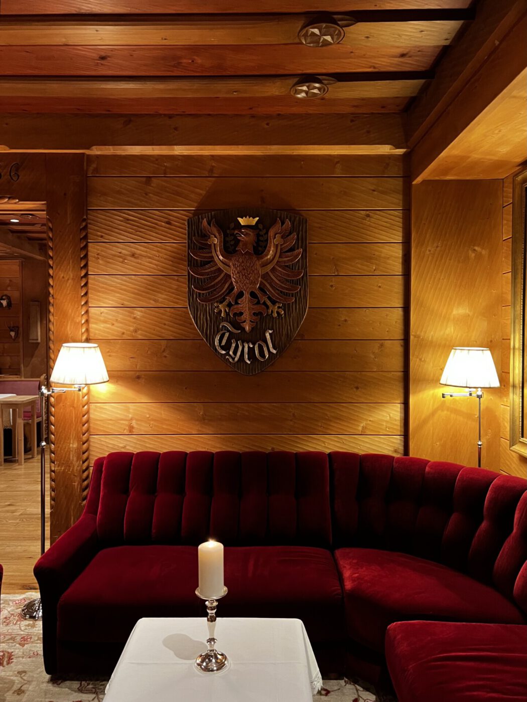 hotel tyrol living room; dimly lit and wood paneled walls with red couches