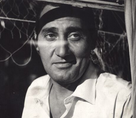 black and white photo of man looking out of a window with a white shirt