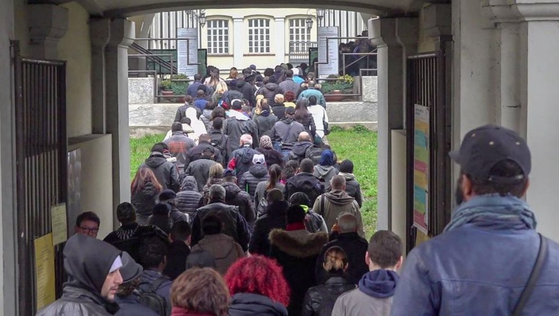 a large crowd and line of people outside an Italian bureaucratic building