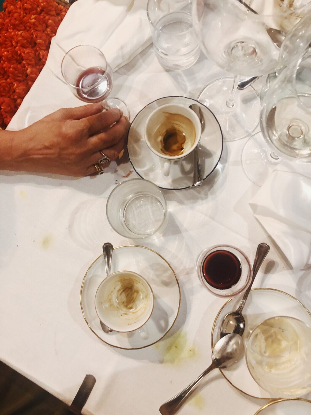 A table at the end of a meal with empty gelato and espresso cups and almost-finished wine glasses