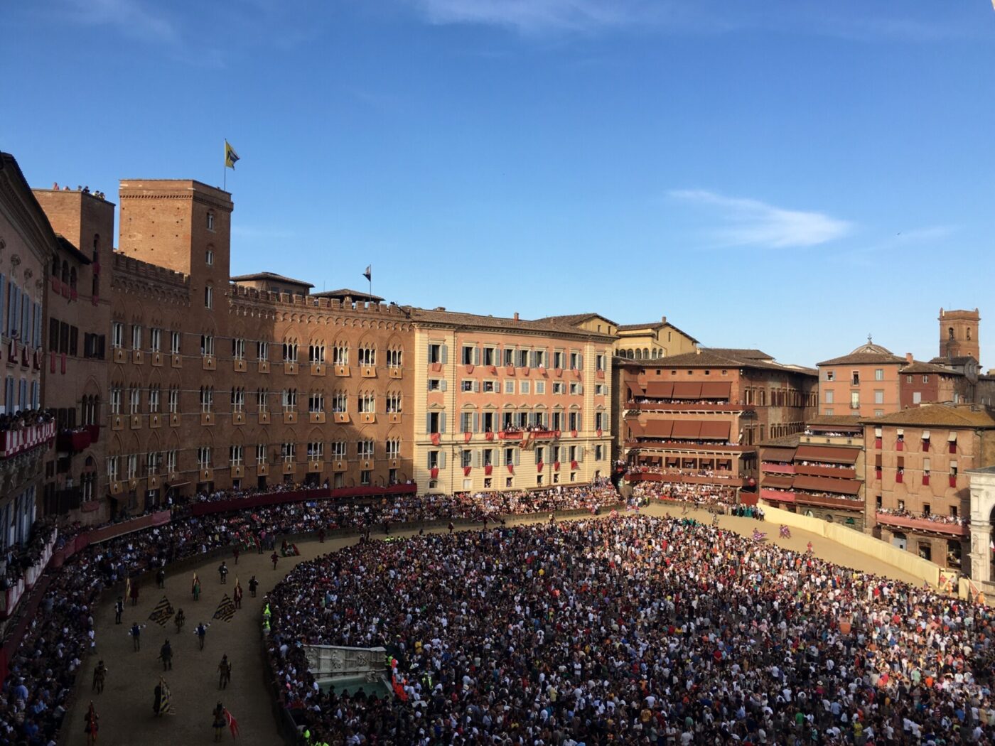 an overhead picture of horses running along the track and crowd of people in the Palio di Siena