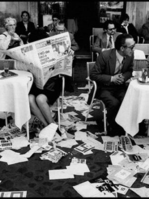 black and white photo from May 1974 in Rome of many people outside a bar and the ground is covered with newspapers