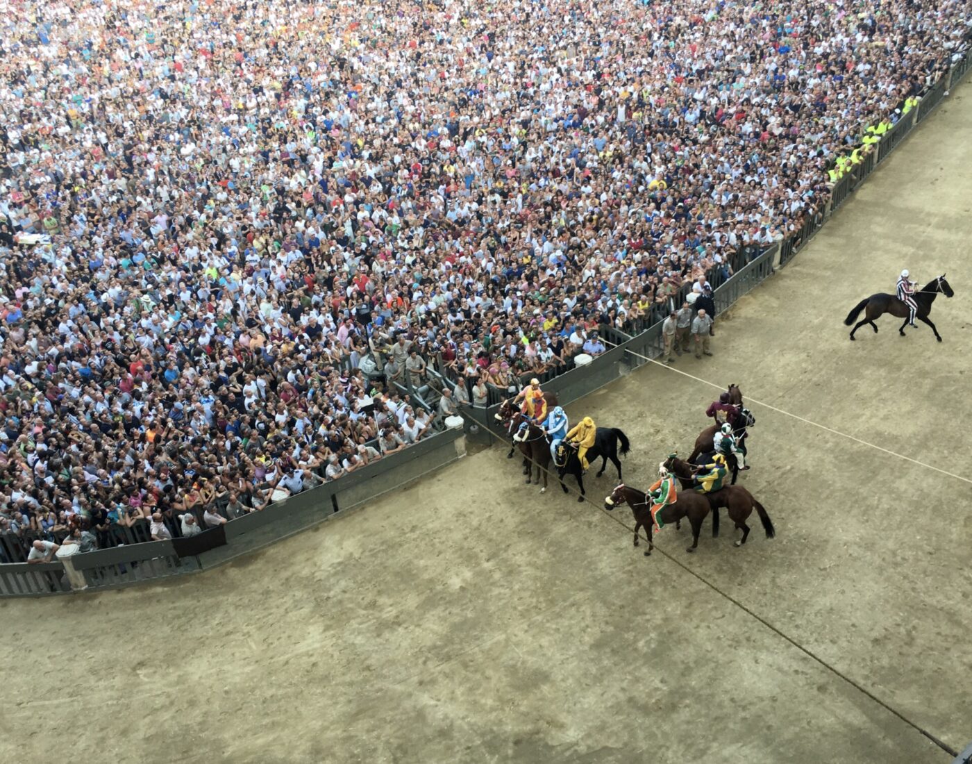 horses running along the track and crowd of people in the Palio di Siena