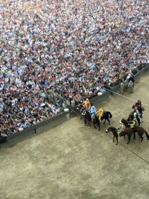 horses running along the track and crowd of people in the Palio di Siena