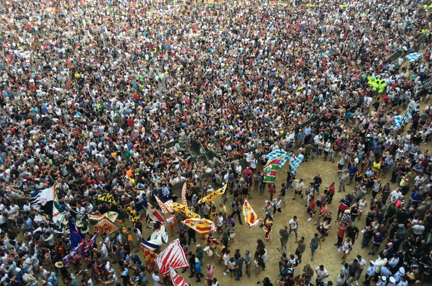 a massive crowd waving flags and packed into the piazza in Siena for the Palio
