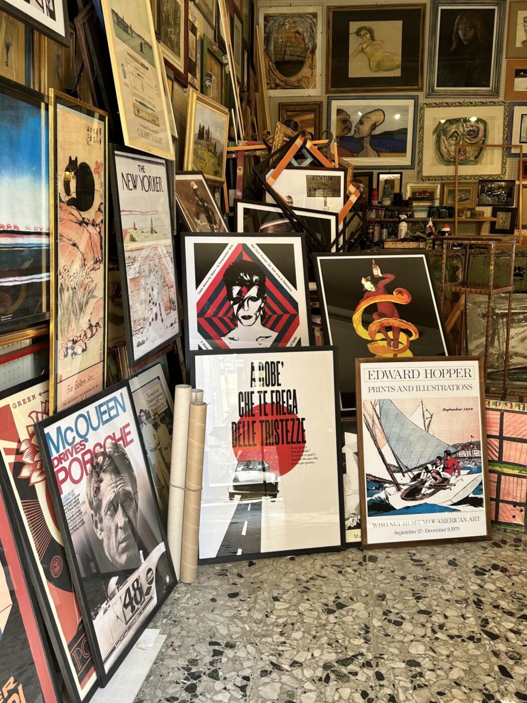 many posters and framed pictures stacked haphazardly into the corner of a store