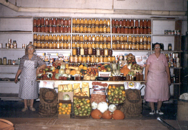 two Italian grandmas in the kitchen with dozens of jars and produce stacked between them