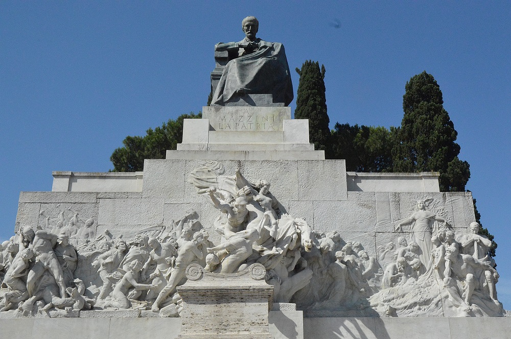 a statue of Mazzini in bronze sitting on top of a scene carved into marble in Roma