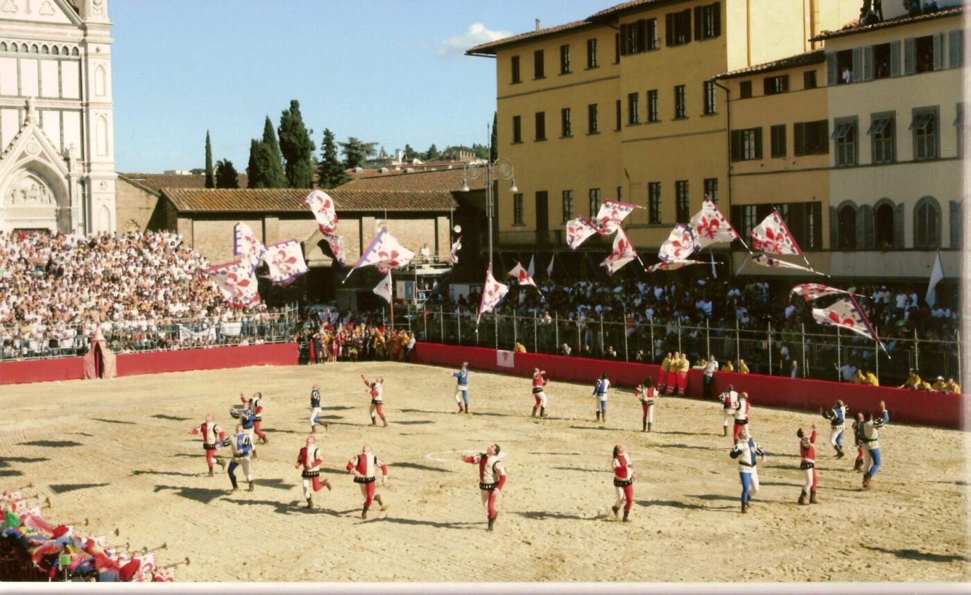 the sand-filled Piazza Santa Croce in Florence preparing for the calcio storico as a circle of men throw flags