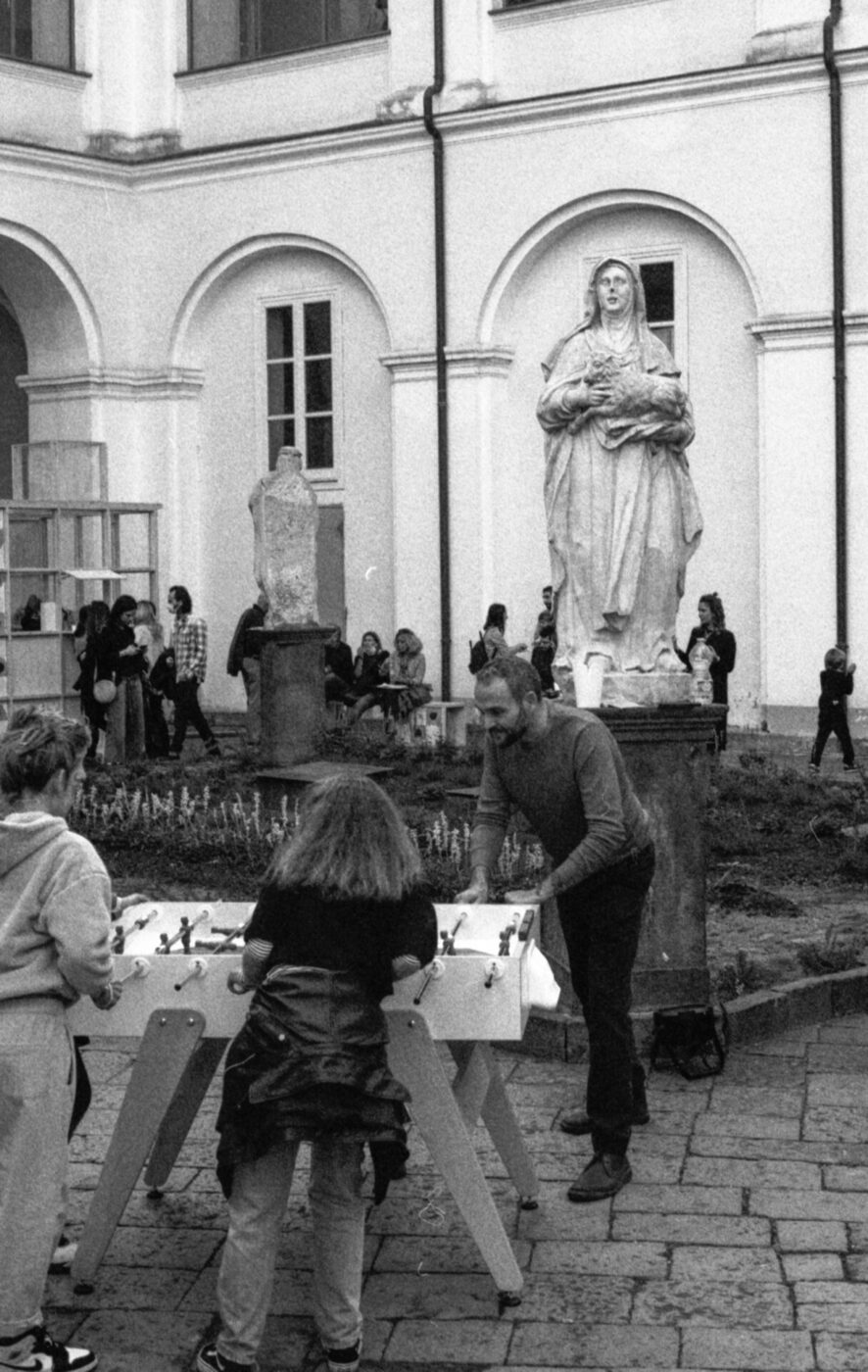 A black and white photo of people playing table football in a piazza in Naples